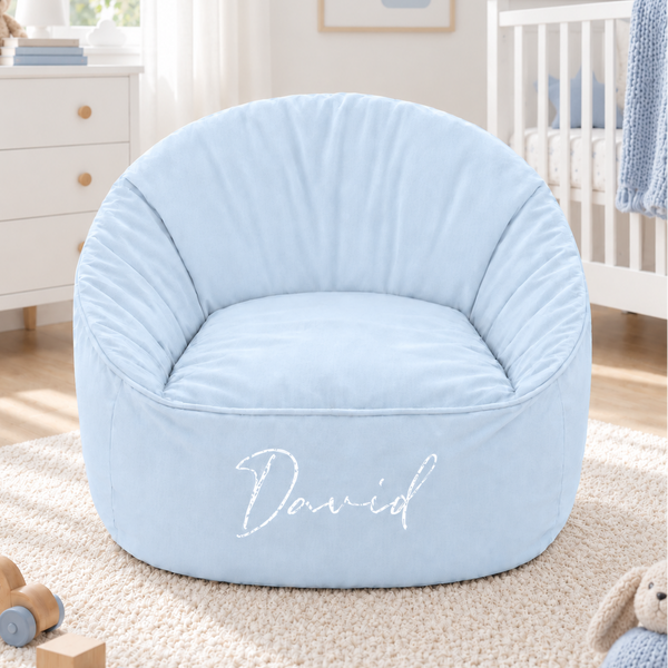 A light blue fabric bean bag chair with the name 'David' embroidered in white script on the front, set in a styled children's bedroom.